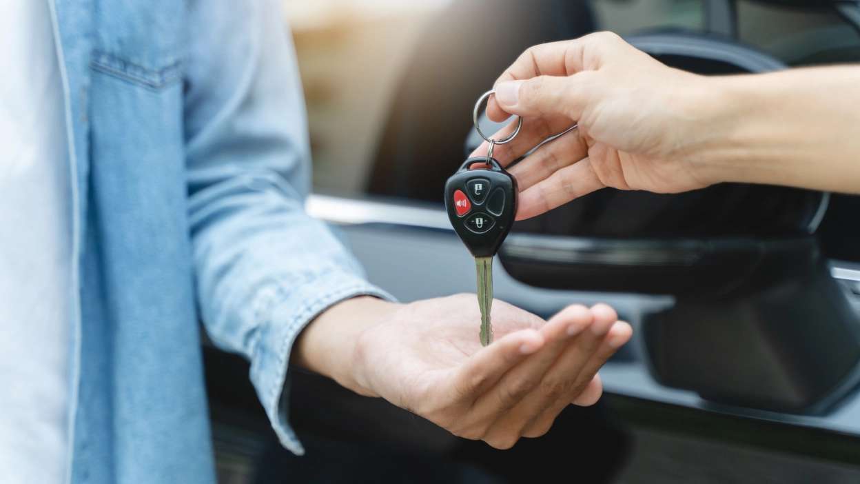 mão de uma pessoa a entregar as chaves do carro na mão de outra pessoa